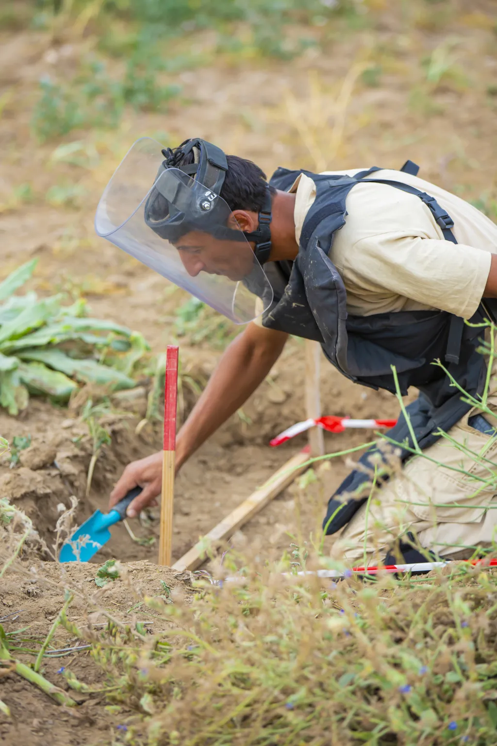 Manual Mine Clearance Deminer with a trowel in a demining lane